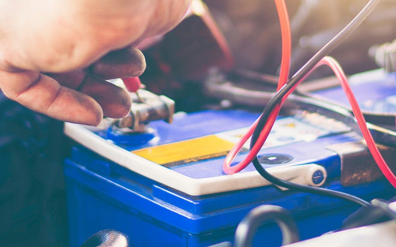 Technician connecting cables to a car battery